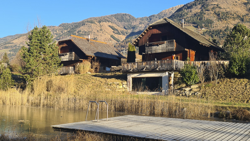 blick auf chalet eingezäunt mit eingezäunter terrasse am badeteich in kärnten moserhof